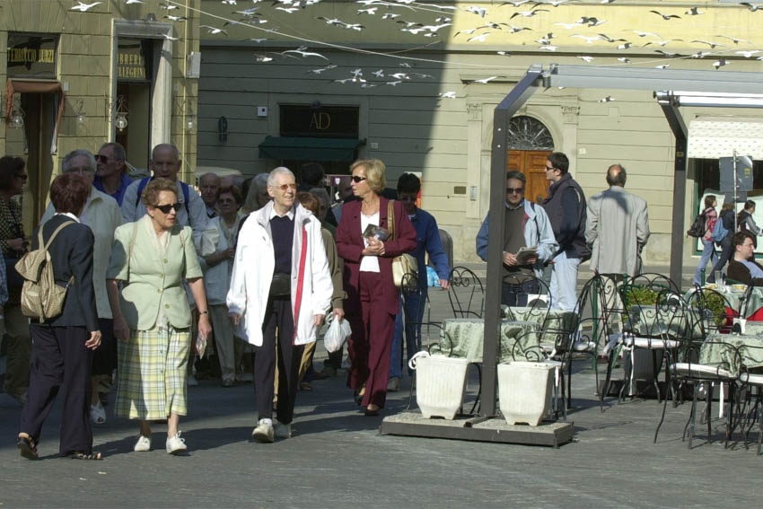 Passanti in una piazza di Arezzo nel 2001 sotto i gabbiani sospesi dell'installazione Cracking Art