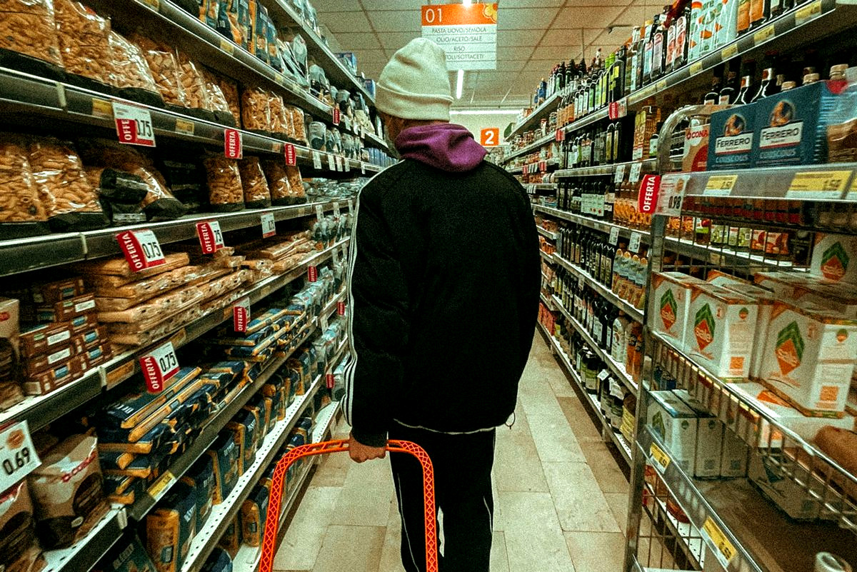 arezzo-spesa-supermercato- Persona di spalle mentre fa la spesa in un supermercato, tra prezzi e offerte.
