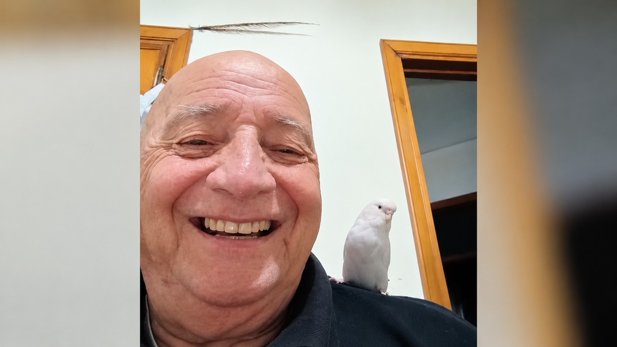 Cesare Fracassi sorridente con la pappagallina Lucy sulla spalla.